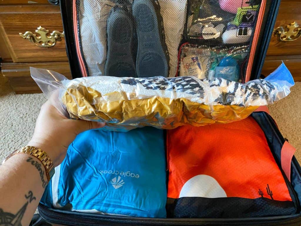 Clothes in a vacuum bag in front of a small suitcase