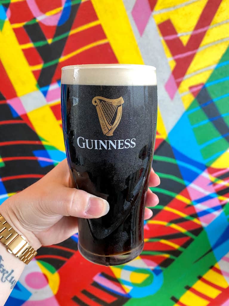 Pint of Guinness in front of a colorful mural