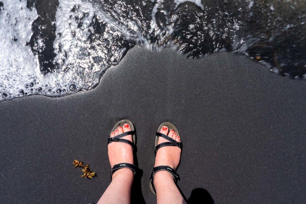 Feet on a black sand beach