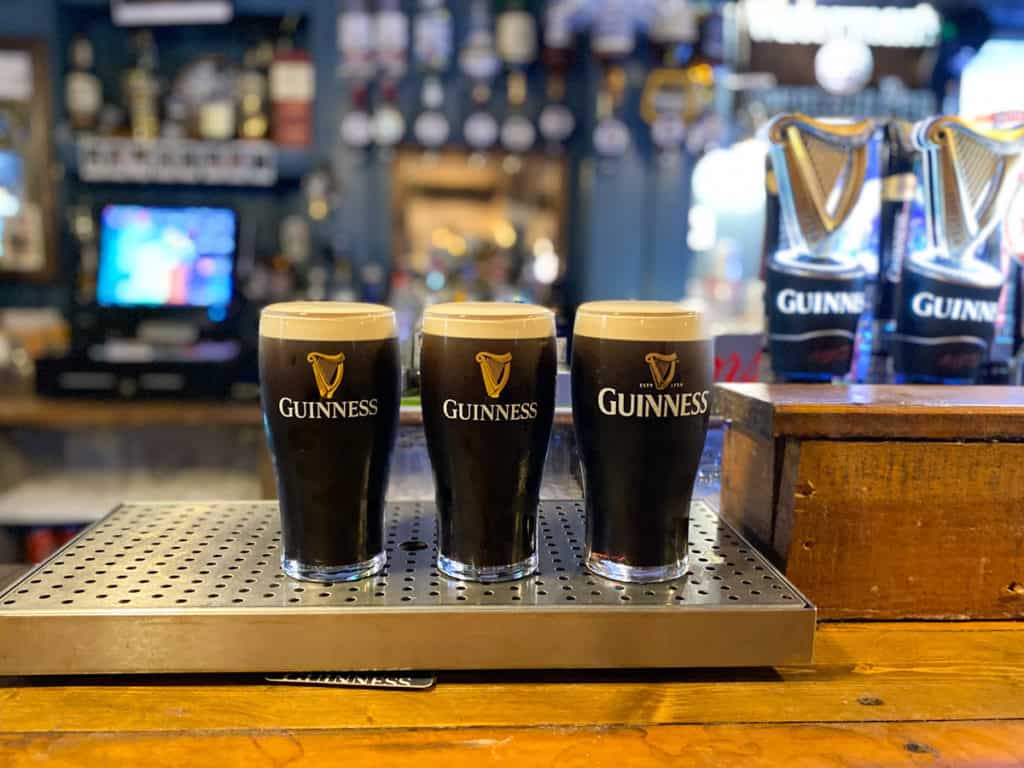 Three pints of Guinness lined up on a bar